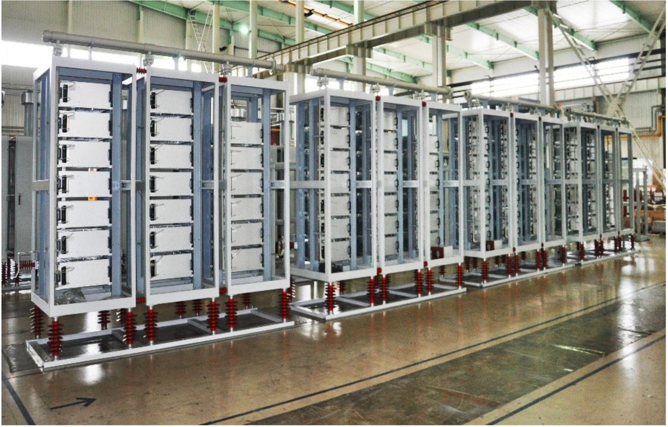 A row of tall medium-voltage converter cabinets standing on insulators in an assembly hall.